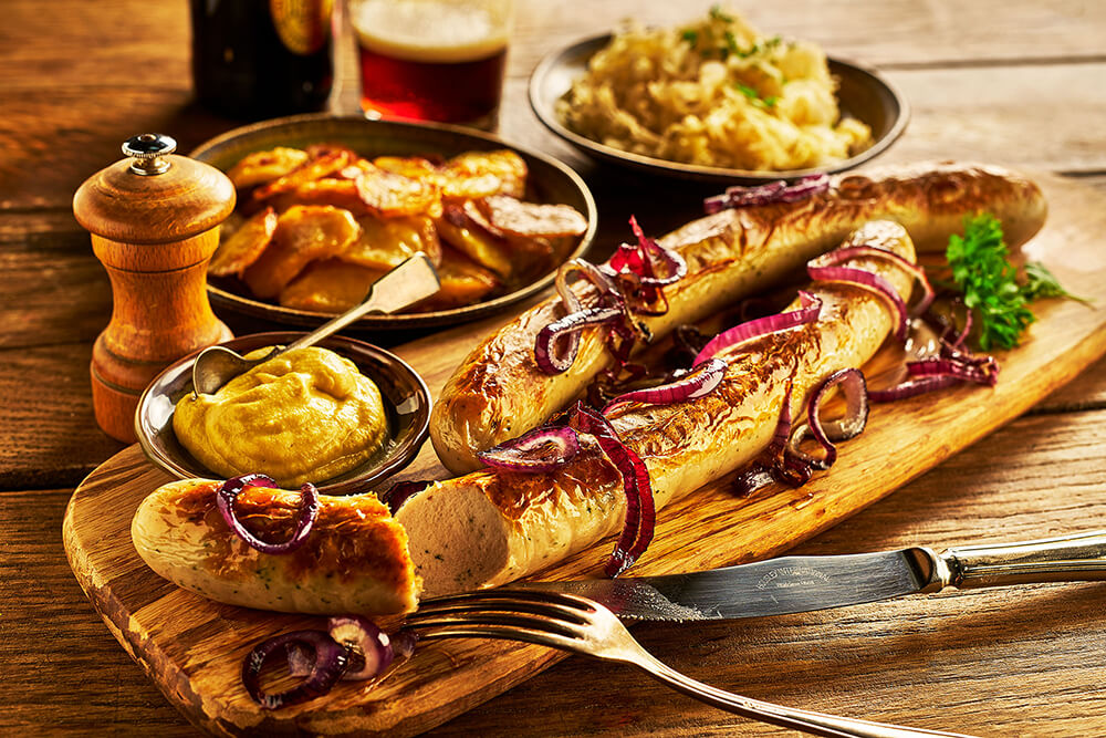 Bratwurst sausage on wooden board with potatoes and mustard on the side
